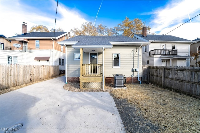 back of property with a shingled roof and fence