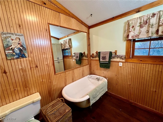 bathroom featuring hardwood / wood-style flooring, a textured ceiling, lofted ceiling, wooden walls, and toilet