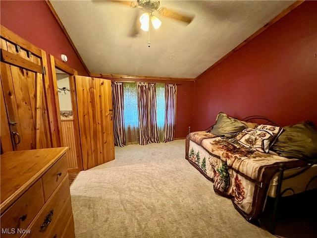 bedroom featuring carpet floors, lofted ceiling, ceiling fan, and wooden walls