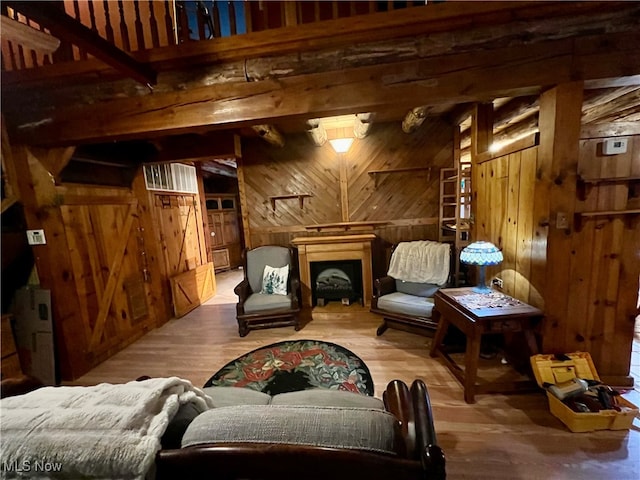 living area with hardwood / wood-style flooring, wooden walls, and beam ceiling