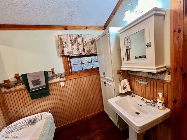 bathroom featuring wooden walls, hardwood / wood-style floors, crown molding, and a textured ceiling