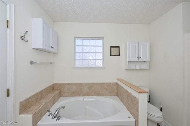 bathroom with toilet, a washtub, and a textured ceiling