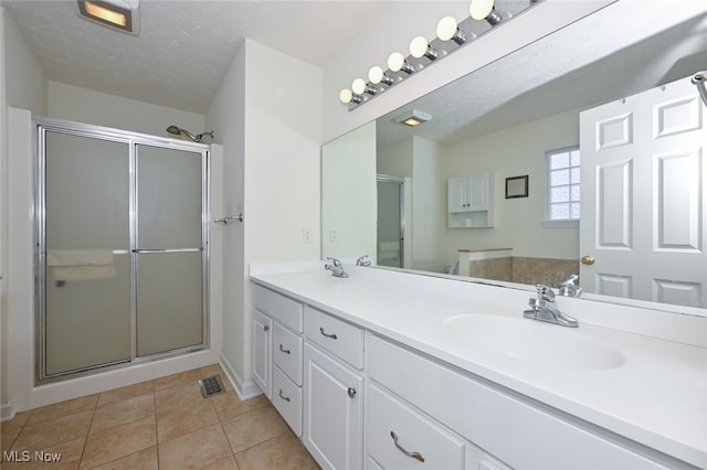 bathroom featuring vanity, tile patterned floors, a textured ceiling, and an enclosed shower