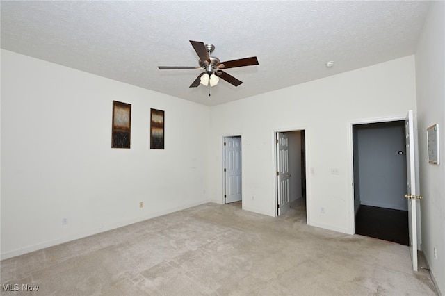 unfurnished bedroom with a textured ceiling, light carpet, and ceiling fan