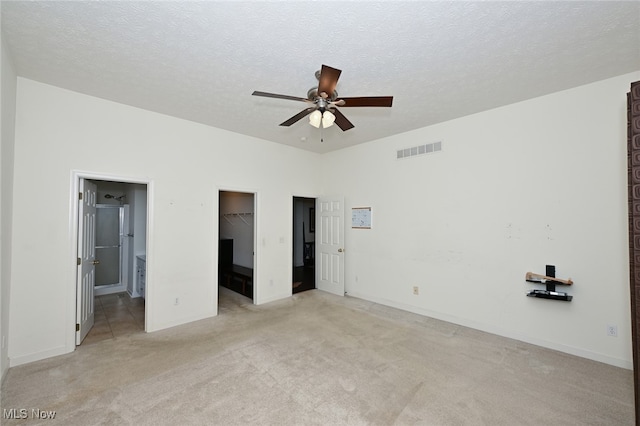 unfurnished bedroom with light carpet, ensuite bathroom, ceiling fan, a spacious closet, and a closet