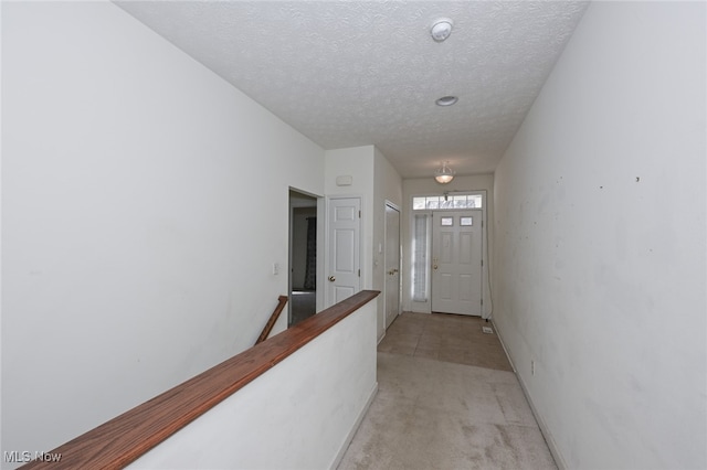 hall with a textured ceiling and light carpet