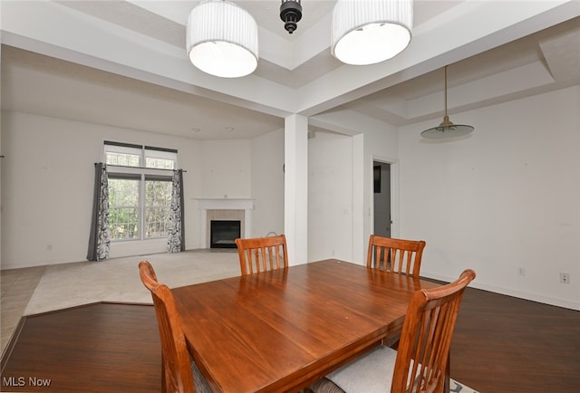 dining room featuring a tiled fireplace and a tray ceiling