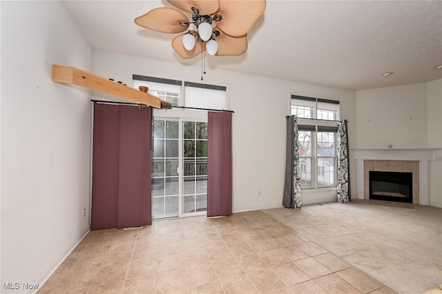 unfurnished living room featuring light carpet, ceiling fan, and a tile fireplace