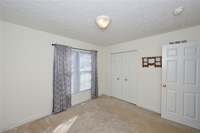 unfurnished bedroom with a closet, a textured ceiling, and light carpet