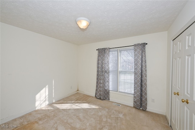 carpeted spare room featuring a textured ceiling