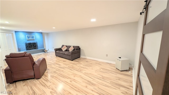 living room with a barn door, light hardwood / wood-style floors, and a fireplace