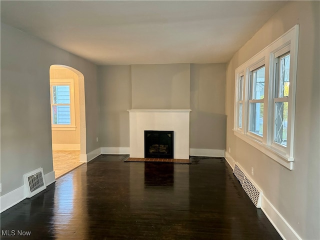 unfurnished living room with a wealth of natural light and dark hardwood / wood-style floors