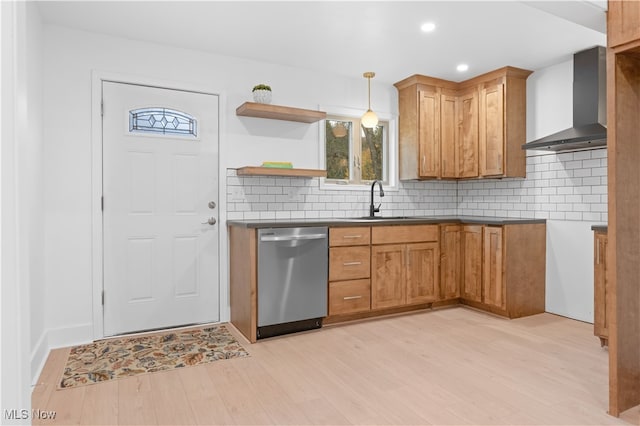 kitchen featuring wall chimney exhaust hood, sink, stainless steel dishwasher, pendant lighting, and light hardwood / wood-style flooring