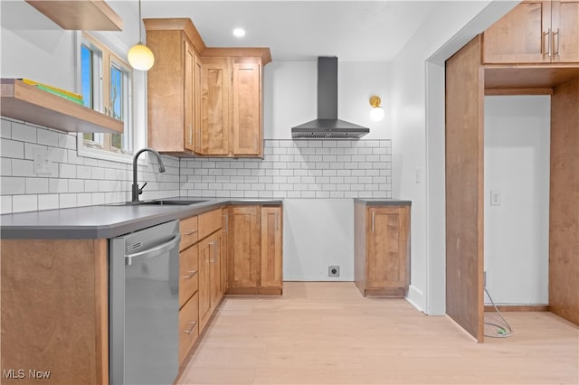 kitchen with dishwasher, wall chimney exhaust hood, hanging light fixtures, sink, and light wood-type flooring