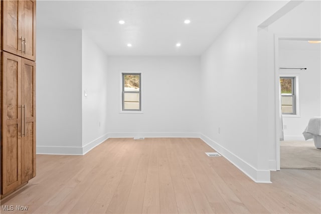 empty room with light hardwood / wood-style floors and a healthy amount of sunlight