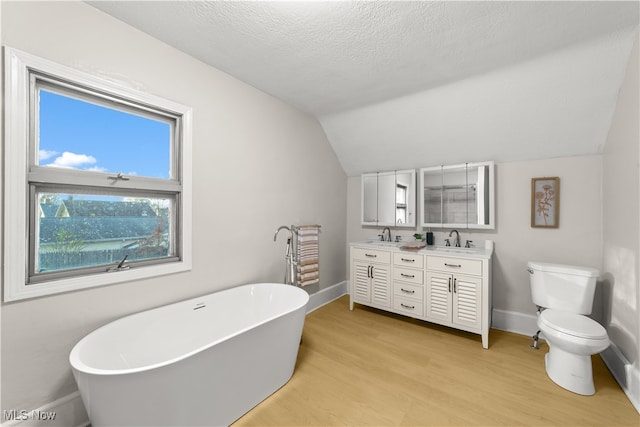 bathroom featuring vanity, a textured ceiling, vaulted ceiling, hardwood / wood-style floors, and a bathing tub