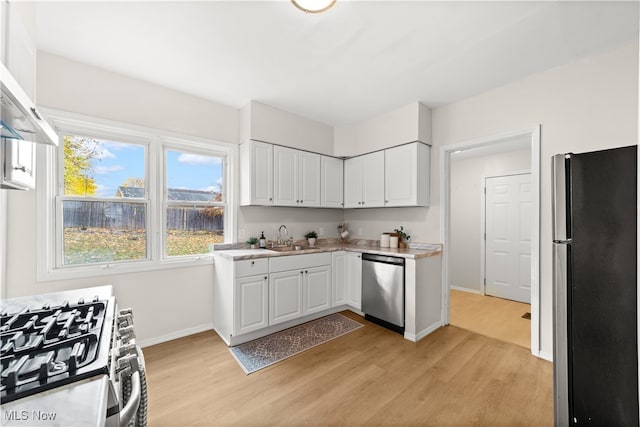 kitchen featuring sink, light hardwood / wood-style flooring, white cabinets, exhaust hood, and appliances with stainless steel finishes