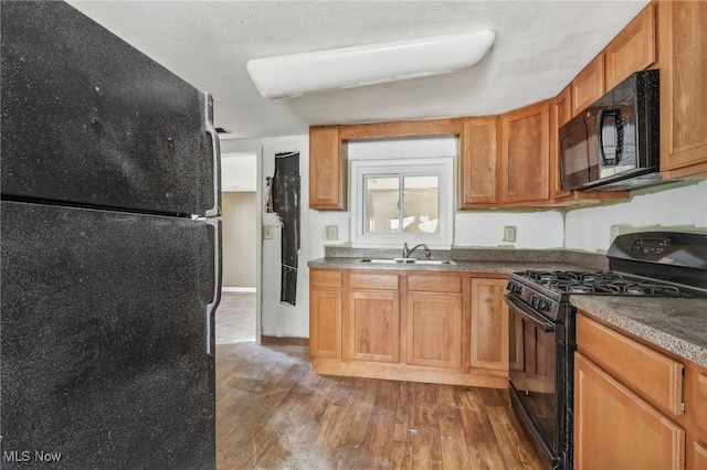 kitchen featuring a textured ceiling, sink, black appliances, and dark hardwood / wood-style flooring