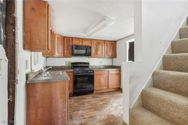 kitchen featuring black appliances, sink, a textured ceiling, and dark hardwood / wood-style floors