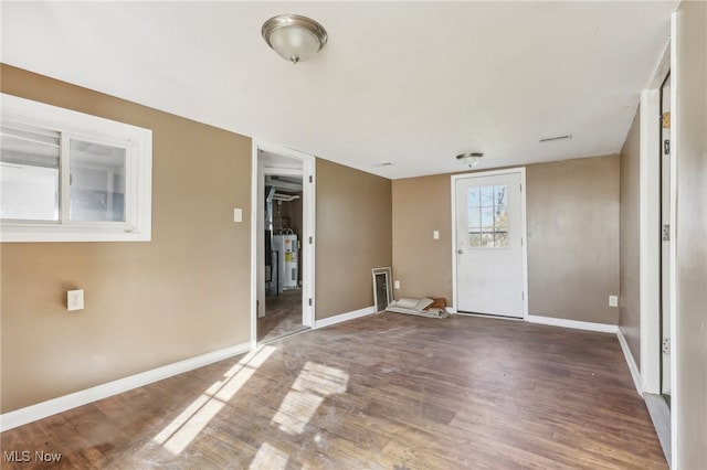 empty room featuring electric water heater and hardwood / wood-style flooring