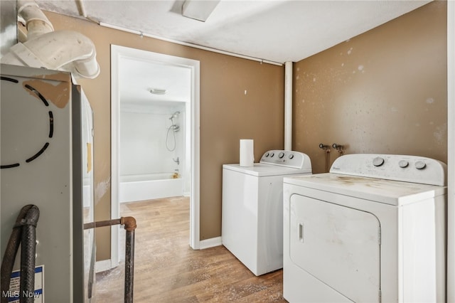 laundry area featuring washing machine and clothes dryer and light hardwood / wood-style flooring