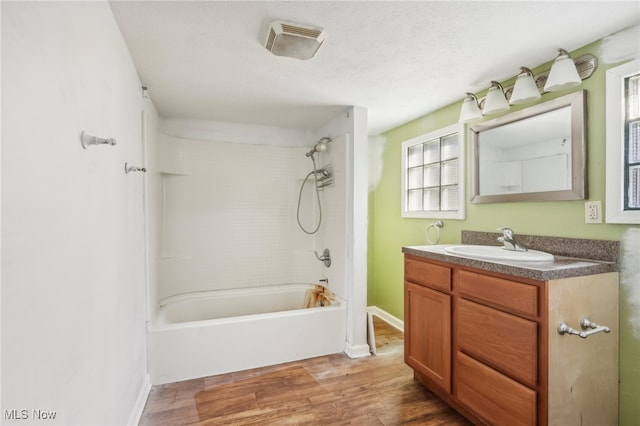 bathroom with vanity, hardwood / wood-style flooring, tiled shower / bath, and a textured ceiling