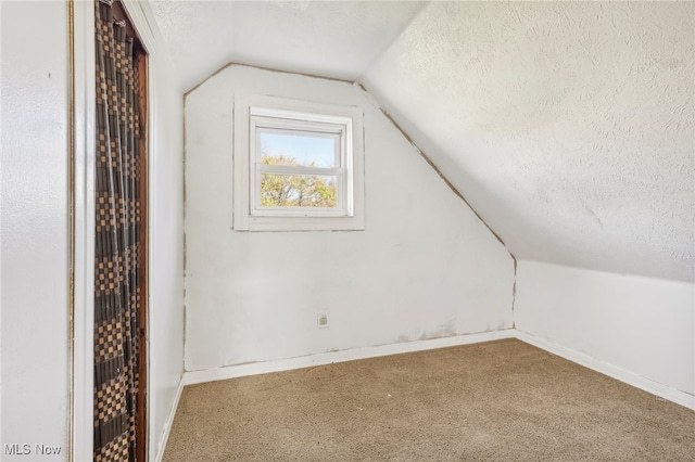 additional living space featuring a textured ceiling, carpet flooring, and vaulted ceiling