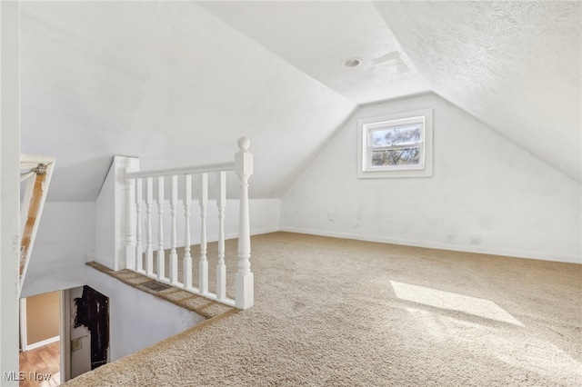 additional living space featuring lofted ceiling, a textured ceiling, and carpet flooring