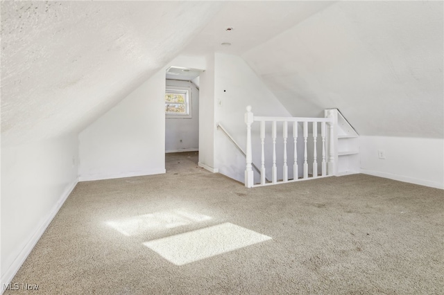 additional living space with lofted ceiling, a textured ceiling, and carpet floors