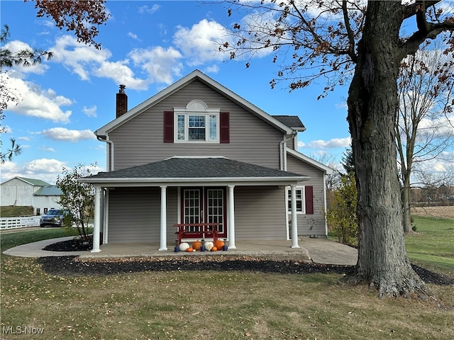 rear view of house featuring covered porch and a yard