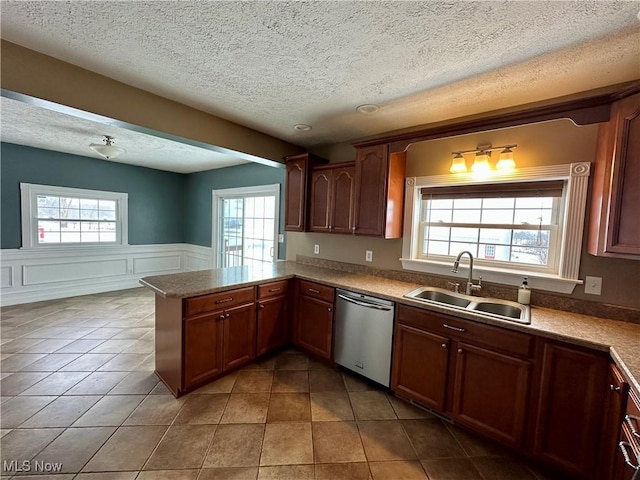 kitchen featuring kitchen peninsula, tile patterned floors, stainless steel dishwasher, and sink