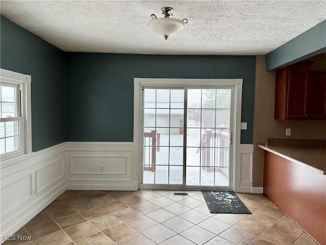 entryway featuring light tile patterned floors, a textured ceiling, and a wealth of natural light