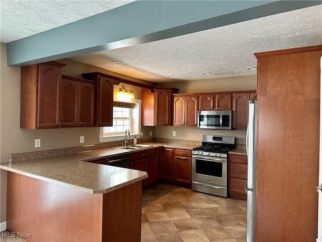 kitchen featuring sink, light tile patterned floors, a textured ceiling, appliances with stainless steel finishes, and kitchen peninsula