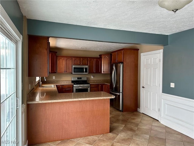 kitchen featuring a textured ceiling, sink, kitchen peninsula, and stainless steel appliances