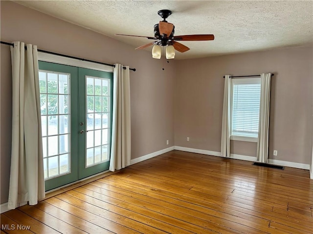 spare room featuring french doors, plenty of natural light, ceiling fan, and wood-type flooring