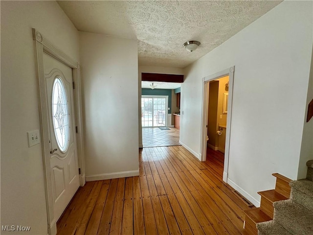 foyer entrance with a textured ceiling and light wood-type flooring