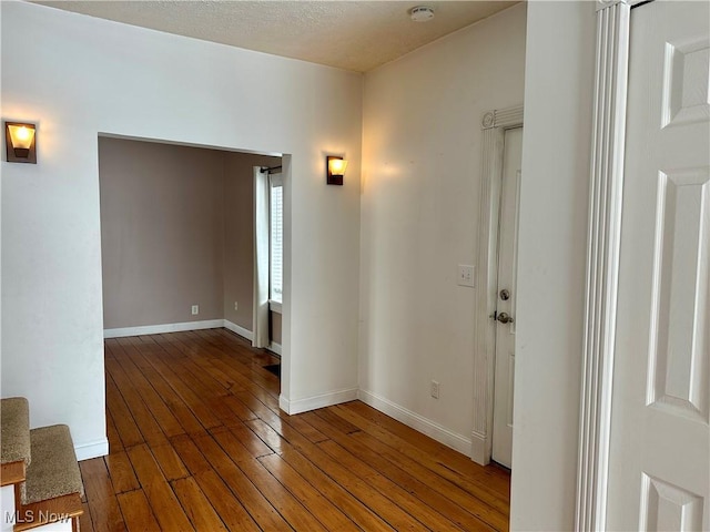 hall with a textured ceiling and dark hardwood / wood-style floors