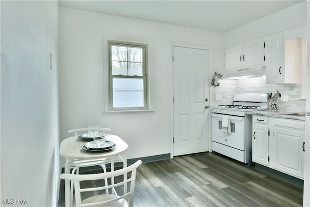 kitchen featuring dark wood-type flooring, white gas range, white cabinetry, and decorative backsplash