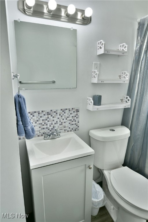 bathroom with decorative backsplash, vanity, and toilet