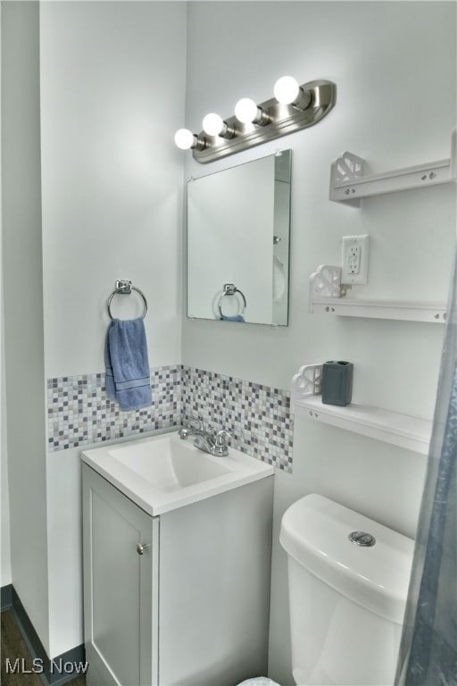 bathroom featuring toilet, vanity, and decorative backsplash