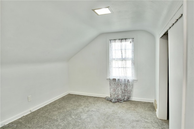 additional living space featuring lofted ceiling and light carpet