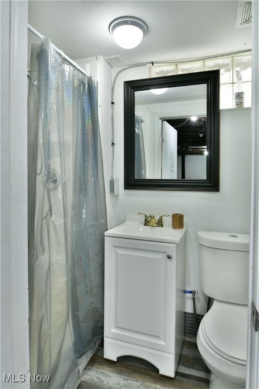 bathroom with curtained shower, wood-type flooring, vanity, and toilet