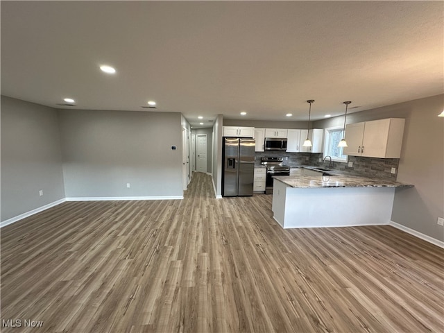 kitchen featuring stainless steel appliances, light wood-type flooring, pendant lighting, sink, and kitchen peninsula