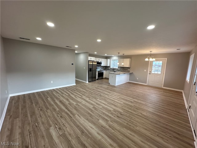 unfurnished living room featuring light hardwood / wood-style flooring, sink, and an inviting chandelier