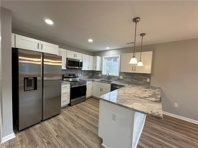 kitchen featuring kitchen peninsula, hanging light fixtures, sink, white cabinetry, and appliances with stainless steel finishes