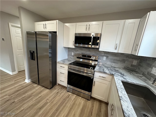 kitchen featuring white cabinetry, stainless steel appliances, sink, and light stone counters