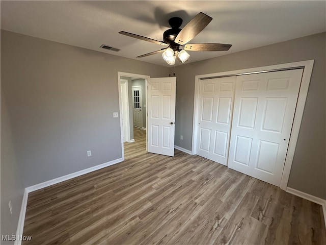 unfurnished bedroom with a closet, wood-type flooring, and ceiling fan