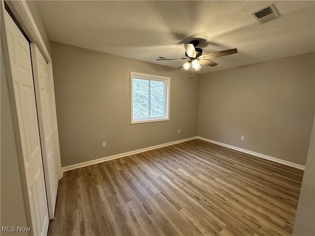 unfurnished bedroom featuring hardwood / wood-style flooring, ceiling fan, and a textured ceiling