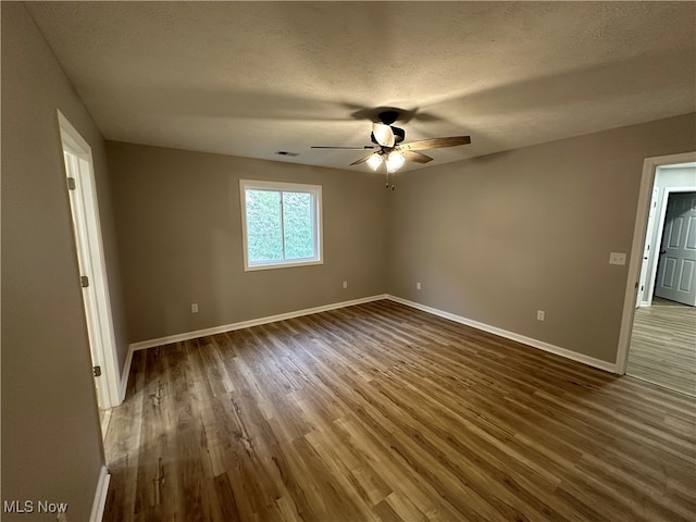 empty room featuring ceiling fan, a textured ceiling, and dark hardwood / wood-style flooring