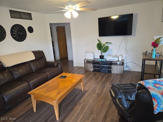 living room featuring ceiling fan and dark hardwood / wood-style floors